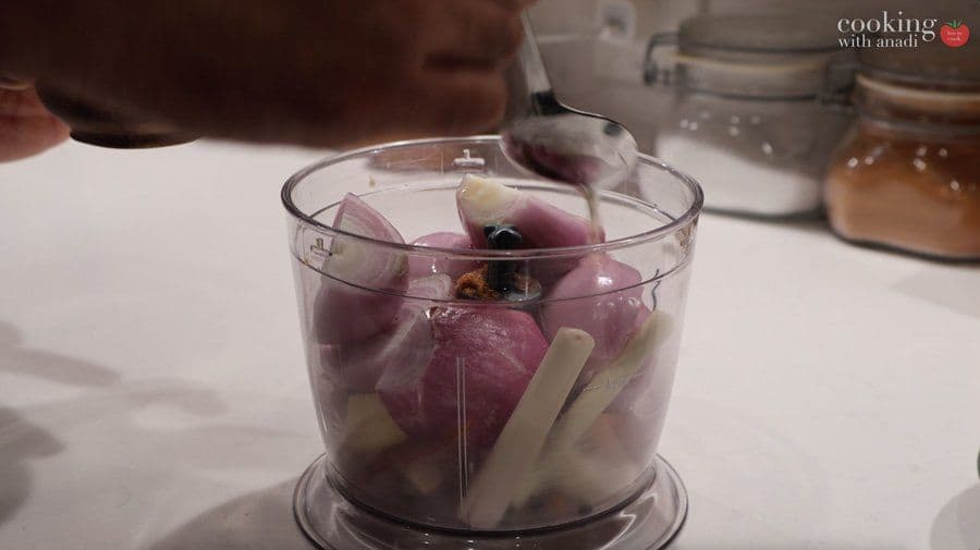 Red onions and garlic being blended in a food processor for rendang spice paste.