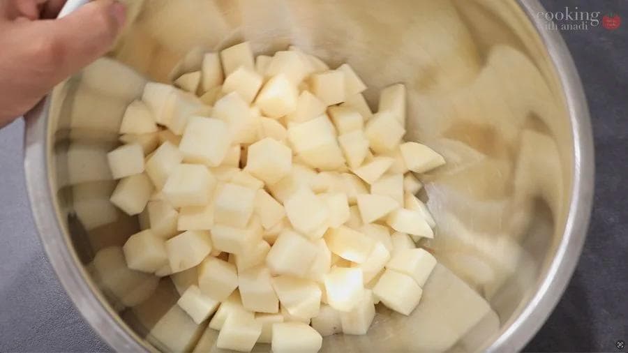 Diced potatoes coated in olive oil in a bowl, ready for air frying.