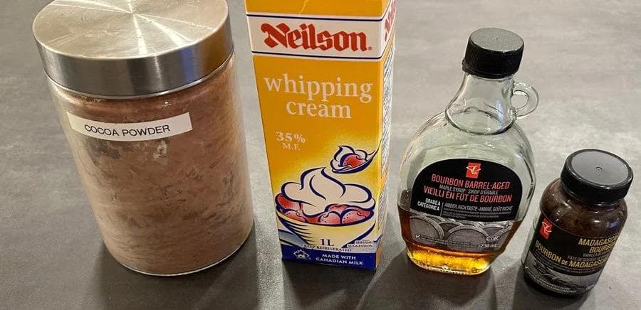 Four ingredients for chocolate whipped cream: cocoa powder, Neilson whipping cream, bourbon barrel-aged vanilla, and Madagascar vanilla extract.