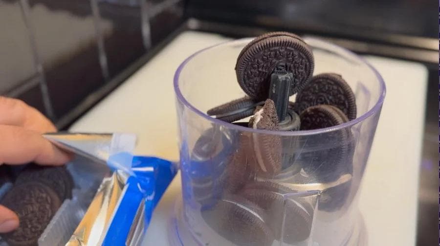Blending Oreo cookies in a food processor to prepare the crust for no-bake mud pie.