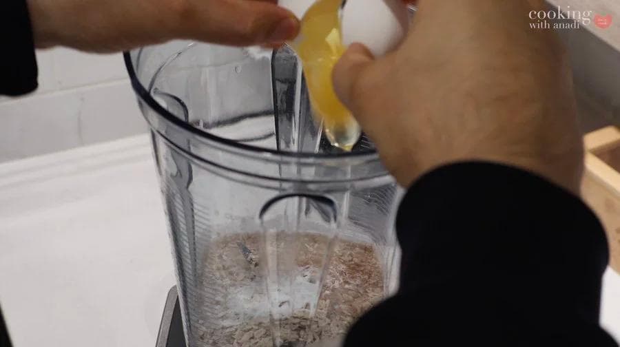 Straining cereal-infused milk through a fine mesh sieve into a blender pitcher using the back of a spoon.