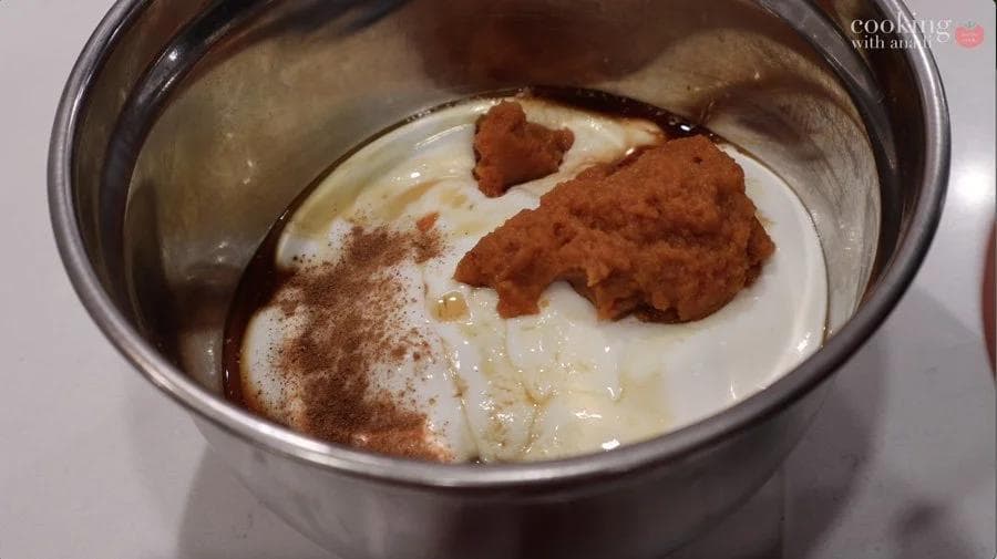 Pumpkin cream cheese filling ingredients in a bowl with cinnamon and pumpkin puee before mixing