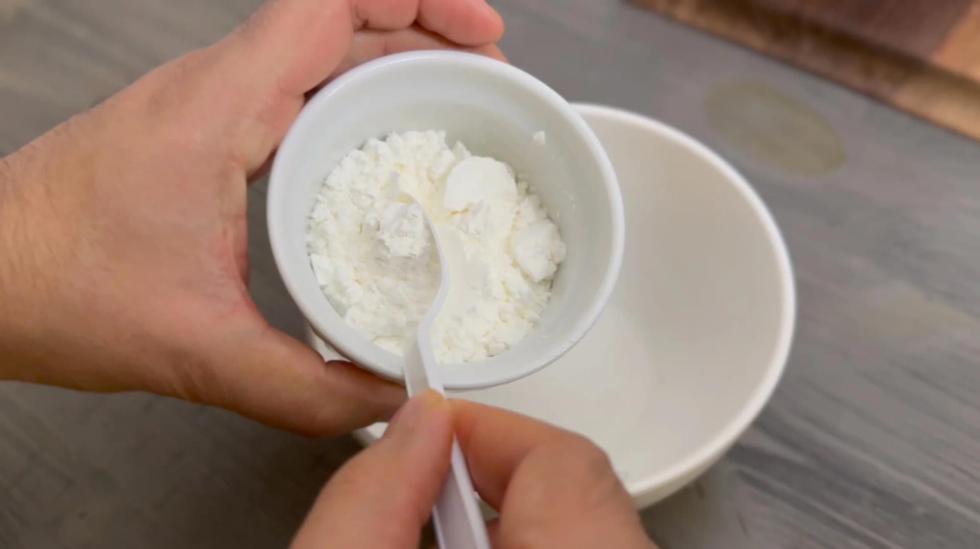 Cornstarch being whisked with cold water in a small white bowl to create a slurry for thickening sauce.